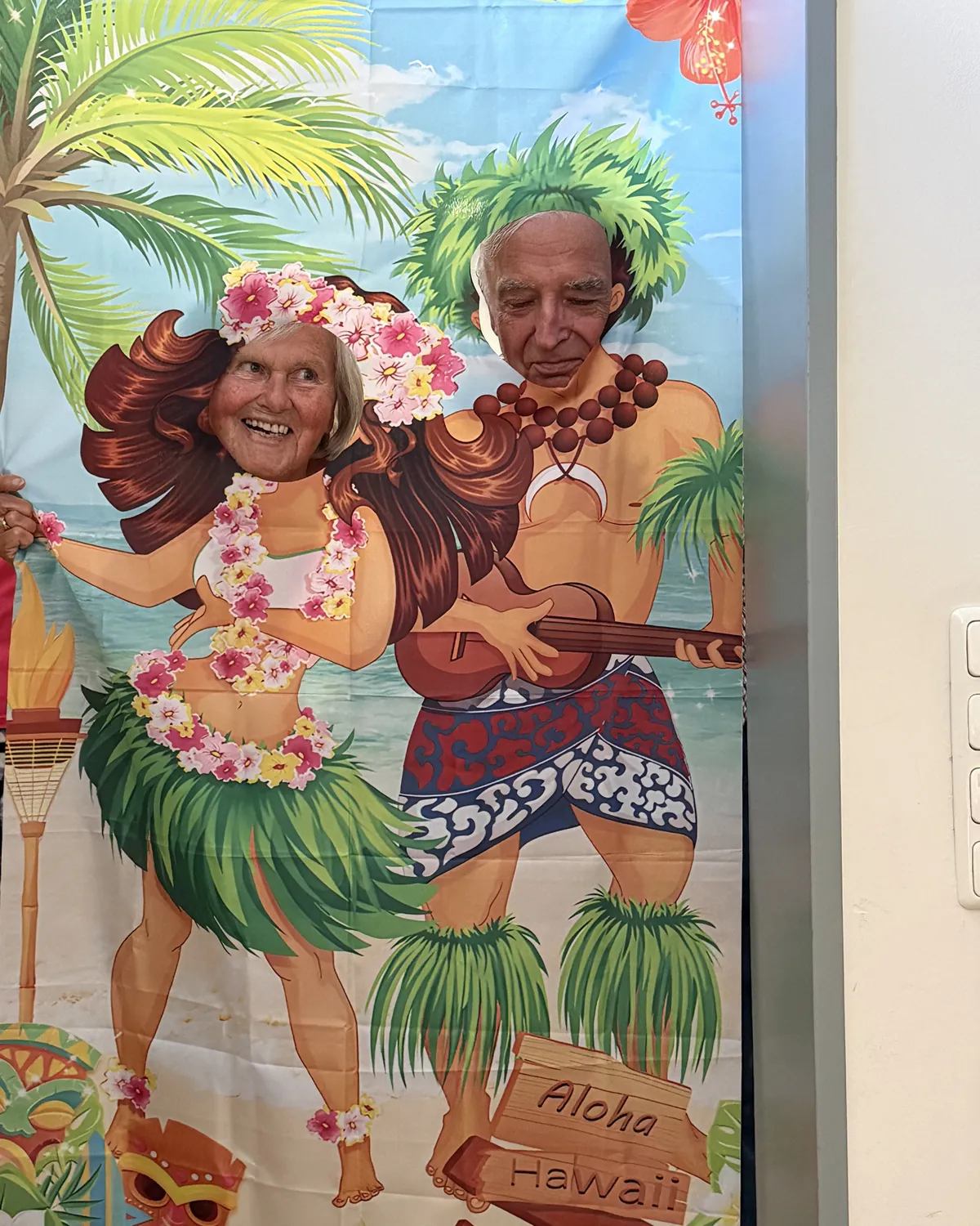 Zwei Gäste lachen hinter einer Hawaii-Fotowand